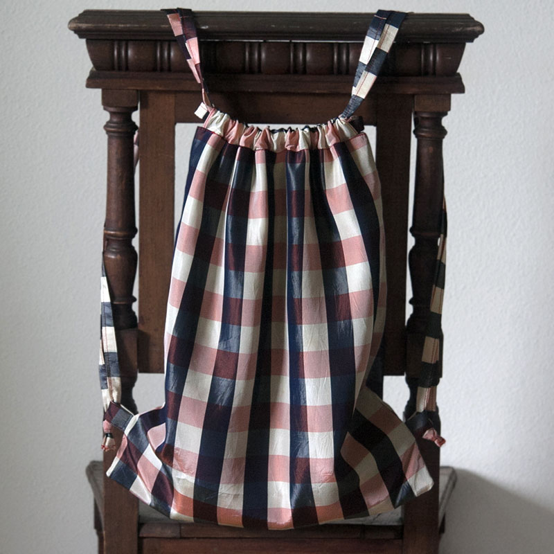 Plaid knapsack hanging on an antique chair.