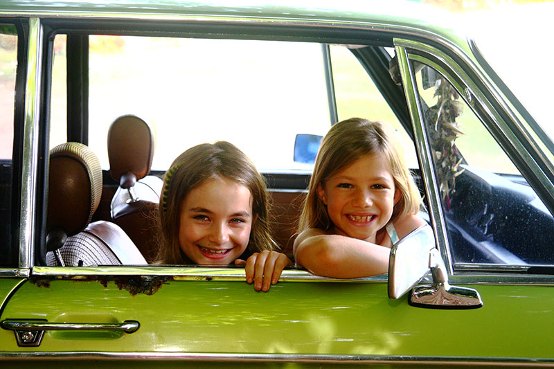 Girls looking out of a vintage car.